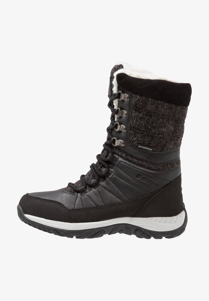 Botte d'hiver noire imperméable avec tige matelassée, avant à lacets et doublure en polaire blanche, conçue pour temps froid et usage extérieur.