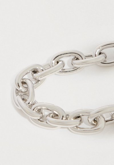 Hõbedast jämedate ovaalsete linkidega käevõru suur plaan, mis on kerge tausta peal lahtises aasas.