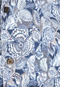 Donkerblauwe stof met witte, lichtblauwe en beige bloemen- en bladsymboolpatronen, met twee bruine knopen aan de linkerkant.