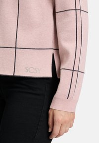 Helles rosa Sweatshirt mit einem schwarzen Karomuster, ausgestattet mit gerippten Bündchen und einem Seitenschlitz. Markenlabel "SCSY" auf dem Saum sichtbar.