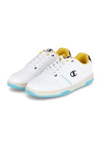 Weiße Sneakers mit einer glatten, synthetischen Oberfläche, gelbem Innenbereich, hellblauen Sohlenakzenten und schwarzer Ferse. Verfügt über Perforationen zur Belüftung.