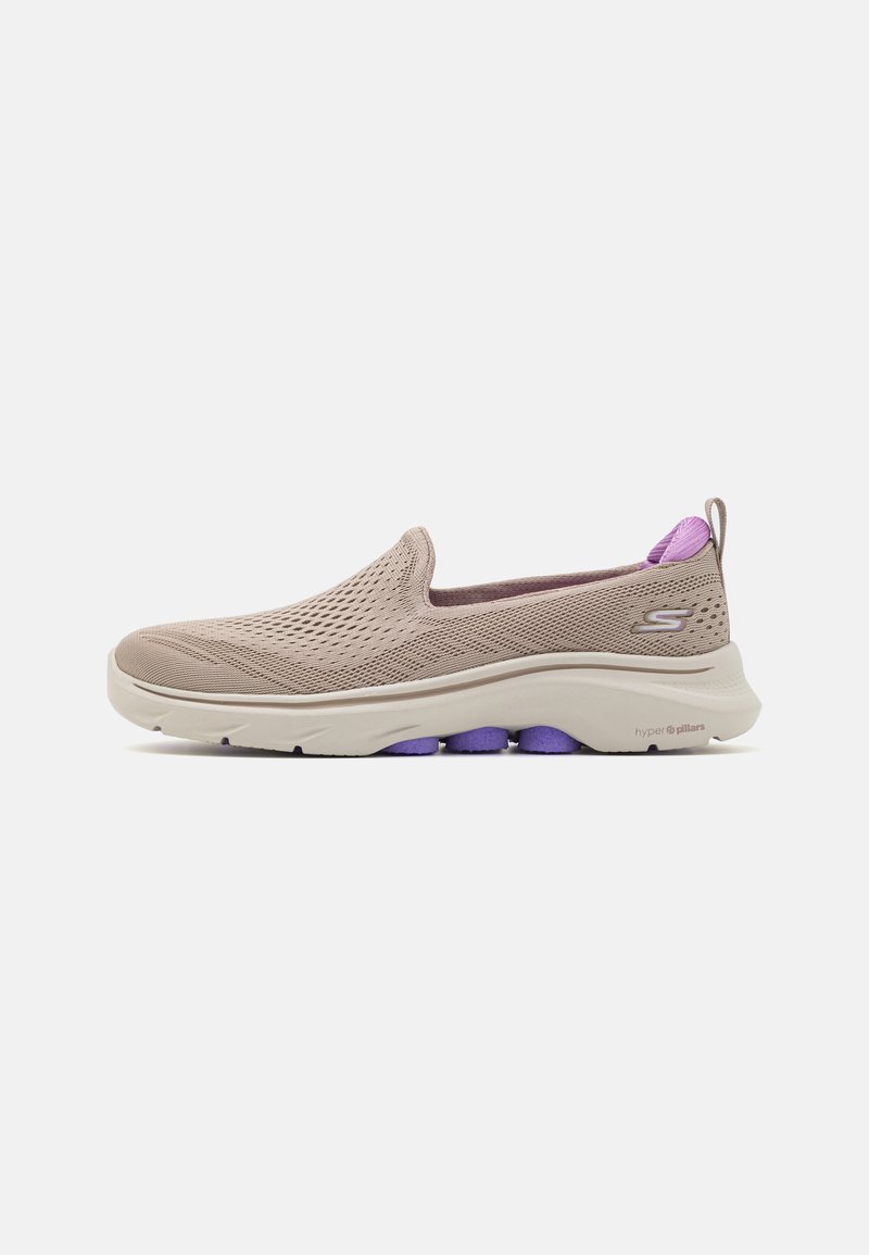 Sapatilhas slip-on em malha bege com detalhes em roxo. Apresenta um bico arredondado, parte superior texturizada e uma entressola branca acolchoada. Design leve.
