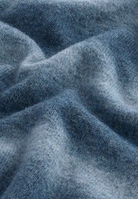 Weiches blaues Strickgewebe mit einer strukturierten Oberfläche, das verschiedene Schattierungen von dunkelblau bis hellblau aufweist und einen subtilen Gradienteneffekt erzeugt.