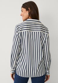 Marineblauwe en witte gestreepte blouse met kraag, lange mouwen en manchetten; ruime pasvorm met een gladde, gepolijste stoftextuur.