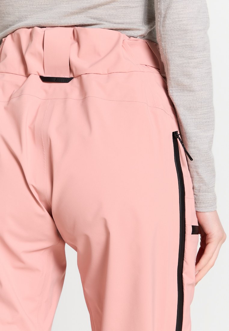 Rosa Hose mit hoher Taille, ausgestattet mit einem gerafften Bund und seitlichen Reißverschlüssen. Der Stoff wirkt glatt mit einem leichten Glanz.