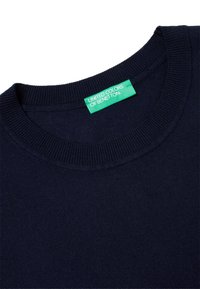 Námorně modrý pletený svetr s kulatým výstřihem, který má na límci zelenou nálepku s nápisem "UNITED COLORS OF BENETTON".