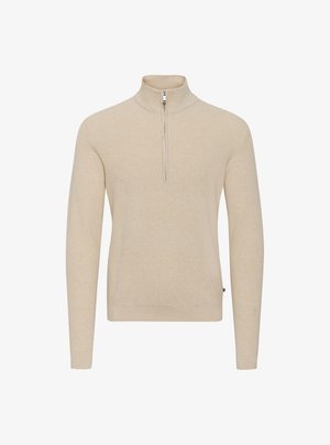 Light beige sweater with a high collar and a short front zipper. Knitted texture, fitted long sleeves, and subtle branding on the side.