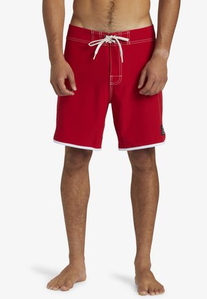 Rote Schwimmshorts mit einem weißen Kordelzug und kontrastierender Naht. Das Design verfügt über einen weißen Saum und ein Logo-Patch an der Seite.
