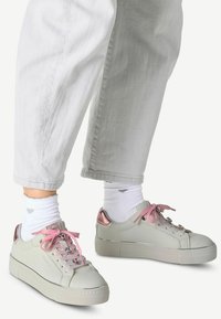 Sneakers grigio chiaro con suola spessa, lacci rosa e dettagli metallici color oro rosa sul tallone. Materiale in pelle liscia con cuciture sottili.