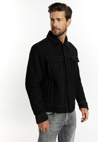 Schwarze Wildlederjacke mit einem strukturierten Schaffellkragen; verfügt über zwei Fronttaschen, vertikale Nahtdetails und kontrastierende Nähte.