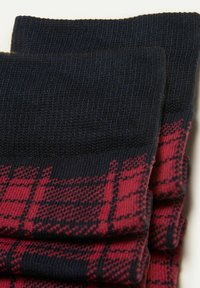 Røde og sorte mønstrede sokker lavet af stof, med en ribbet tekstur ved skaftet og et ternet design på kroppen.