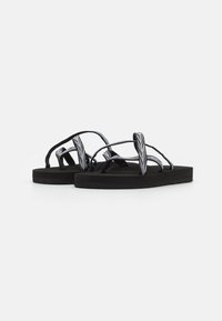 Black flip-flops with woven straps featuring a zigzag pattern, soft footbed, and flat rubber sole. Simple design for casual wear.