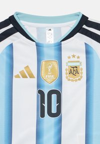 Φανέλα ποδοσφαίρου Αργεντινής με μπλε και λευκές ρίγες, αριθμός 10, χρυσό σήμα πρωταθλητή FIFA 2022, και έμβλημα AFA με τρία αστέρια.