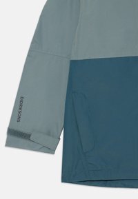 Wasserdichte Jacke mit zweifarbigen Design: Hellgrauer Oberteil und dunkelblauer Teal-Unterteil. Mit verstellbaren Bündchen und einer Seitentasche.