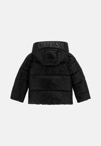 Melnā pārgatavošanas puffer jaka ar kapuci, kurai uz kapuces muguras ir drukāts "GUESS" logo.