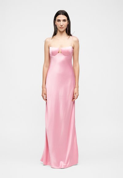 Femme aux longs cheveux foncés portant une robe longue en satin rose clair sans manches avec un bustier structuré et des fines bretelles.