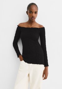 Zwarte off-shoulder top met lange mouwen van een gestructureerde, gekreukte stof; heeft gerimpelde randen bij de halslijn en de mouwboorden.