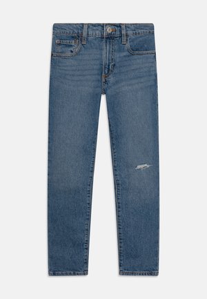 Jean en denim bleu droit avec poches avant et arrière, fermeture par bouton et une petite déchirure usée sur la cuisse droite.