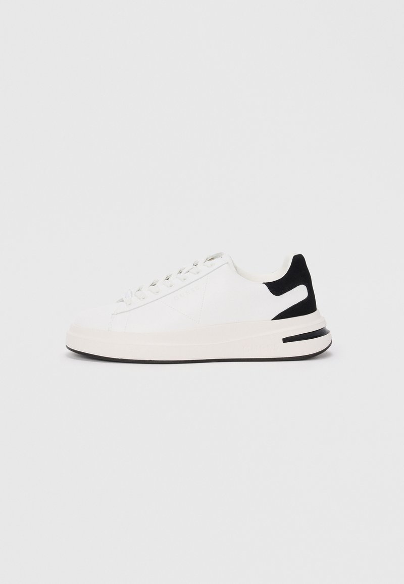 Baskets blanches avec un upper en cuir lisse, accent de talon en suède noir, lacets plats et semelle en caoutchouc texturée. Détail de logo notable sur le côté.