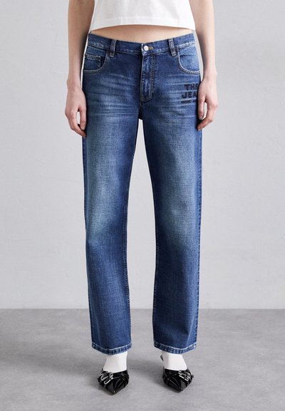 Blugi din denim albastru cu o croială lejeră, dotati cu un sistem de închidere cu nasturi, cinci buzunare și un logo imprimat negru pe față. Material lavabil la mașină.
