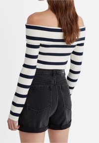 Haut à épaule dénudée en plastique côtelé avec des rayures bleu marine et blanches, associé à un short en denim noir taille haute avec des revers et des poches arrière.