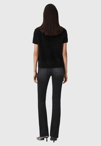Zwart topje met korte mouwen en een textuureffect, gecombineerd met donkergrijze wijde jeans. Soepele stof en een aangesloten pasvorm. Ontwerp met gesloten achterkant.