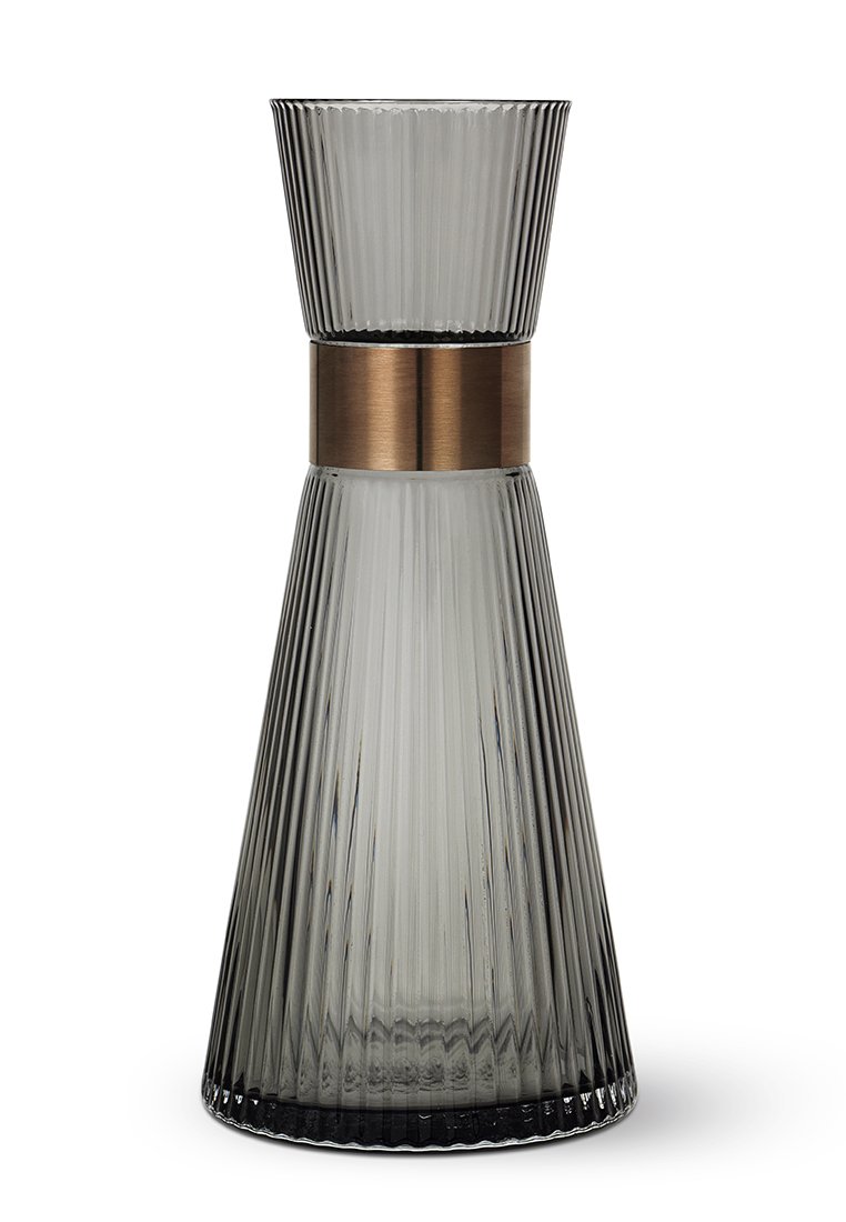 Decantador de vidrio gris con textura acanalada vertical, forma cónica y una banda de metal bronce pulido alrededor del centro. Base lisa.
