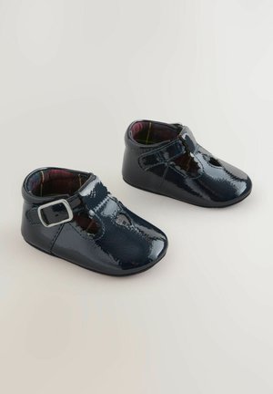 Svarta lackläder babyskor med rund tå, spännestraps och rutigt inre foder; slät textur och elegant design.