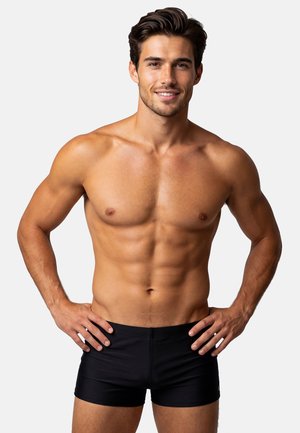 Czarne spodenki kąpielowe o dopasowanym kroju, gładkiej fakturze i elastycznym pasie, prezentowane na modelu o wysportowanej sylwetce.