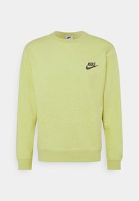 Žlutá mikina s kulatým výstřihem, dlouhými rukávy a malým černým logem Nike na hrudi. Měkká, texturovaná tkanina s melírovaným povrchem.