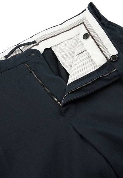 Pantaloni blu navy con zip sul davanti, vita a strisce bianche e chiusura a bottone. Il tessuto appare liscio con una finitura opaca.