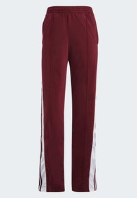 Pantalones deportivos burdeos con cinturilla elástica y cordón, dos bolsillos laterales y rayas blancas a los lados. Fabricados en tejido suave y ligero.