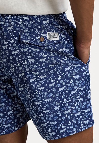 Blå shorts med hvite dyre- og bladmønstre, laget av lett stoff. Har sidelommer og et lite logo-merke med en knapp.