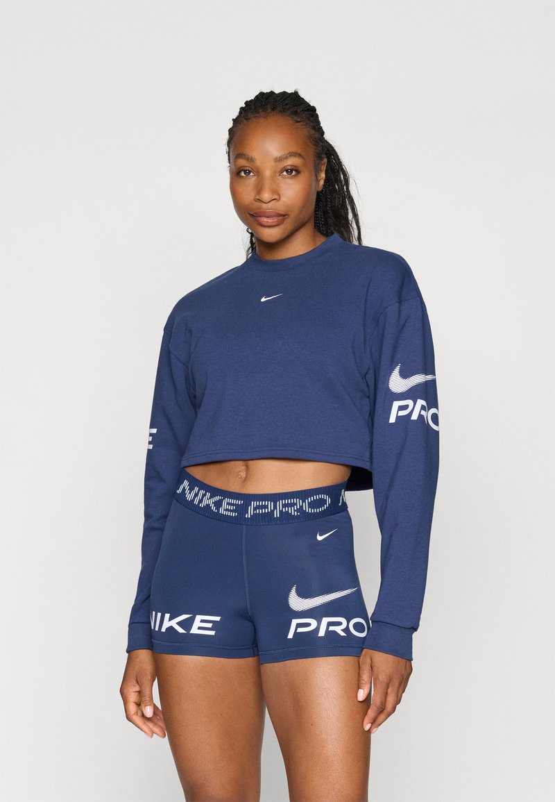 Felpa blu corta con maniche lunghe, con logo Nike bianco. Abbinata a pantaloni corti Pro blu, anch'essi brandizzati, con un cinturino testurizzato.