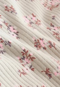 Tessuto ribbed beige con un delicato motivo di piccoli gruppi floreali rosa e marroni.