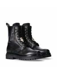 Stivali alla caviglia in pelle nera con un design a lacci, occhielli in metallo, accenti decorativi a forma di gufo e gioiello, e suole in gomma robuste.