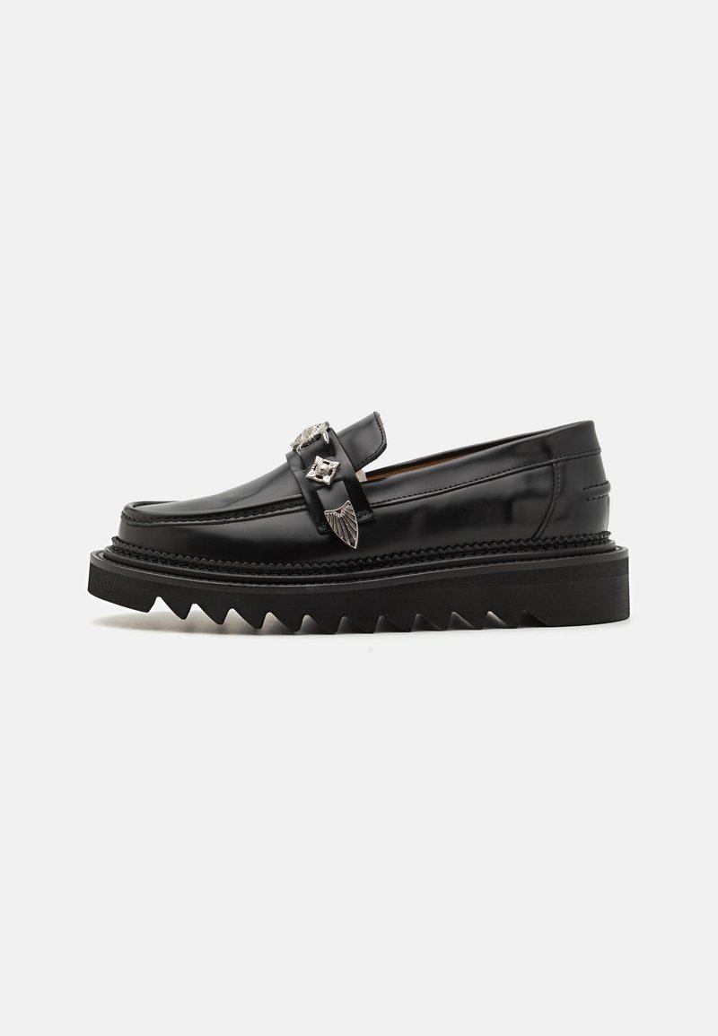 Mustad musta nahast loafers hõbedaste detailidega, tõstetud zigzag tallaga ja sujuva, ümarate joontega disain; sile tekstuur ja läikiv viimistlus.
