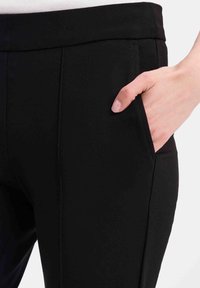 Zwarte broek van elastische stof, met een strak ontwerp, een voorzak en subtiele stiksels langs de naden.