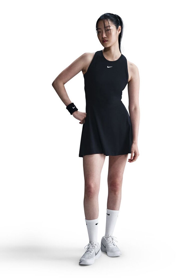 Black athletic dress with a fitted bodice and flared skirt, paired with white Nike socks and shoes, and a black wristband. Notable Nike logo.