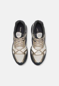 Ett par beige, svarta och vita Reebok Premier Road Plus VI löparskor med snörning, sedda uppifrån mot en vit bakgrund.