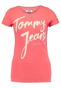 Koralli T-paita pyöreällä kaula-aukolla, jossa valkoinen teksti "Tommy Jeans New York." Valmistettu pehmeästä kankaasta, lyhyet hihat, istuva malli.