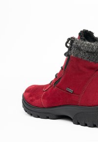 Roter Wildleder-Winterstiefel mit schwarzer Gummisohle, seitlichem Reißverschluss, schwarzen Schnürsenkeln und grauem wollgefüttertem Bündchen.