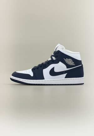 Air Jordan tenisica visokog gornjeg dijela u bijeloj i tamnoplavoj boji s Nike swoosh logotipom i Air Jordan wings logom sa strane.