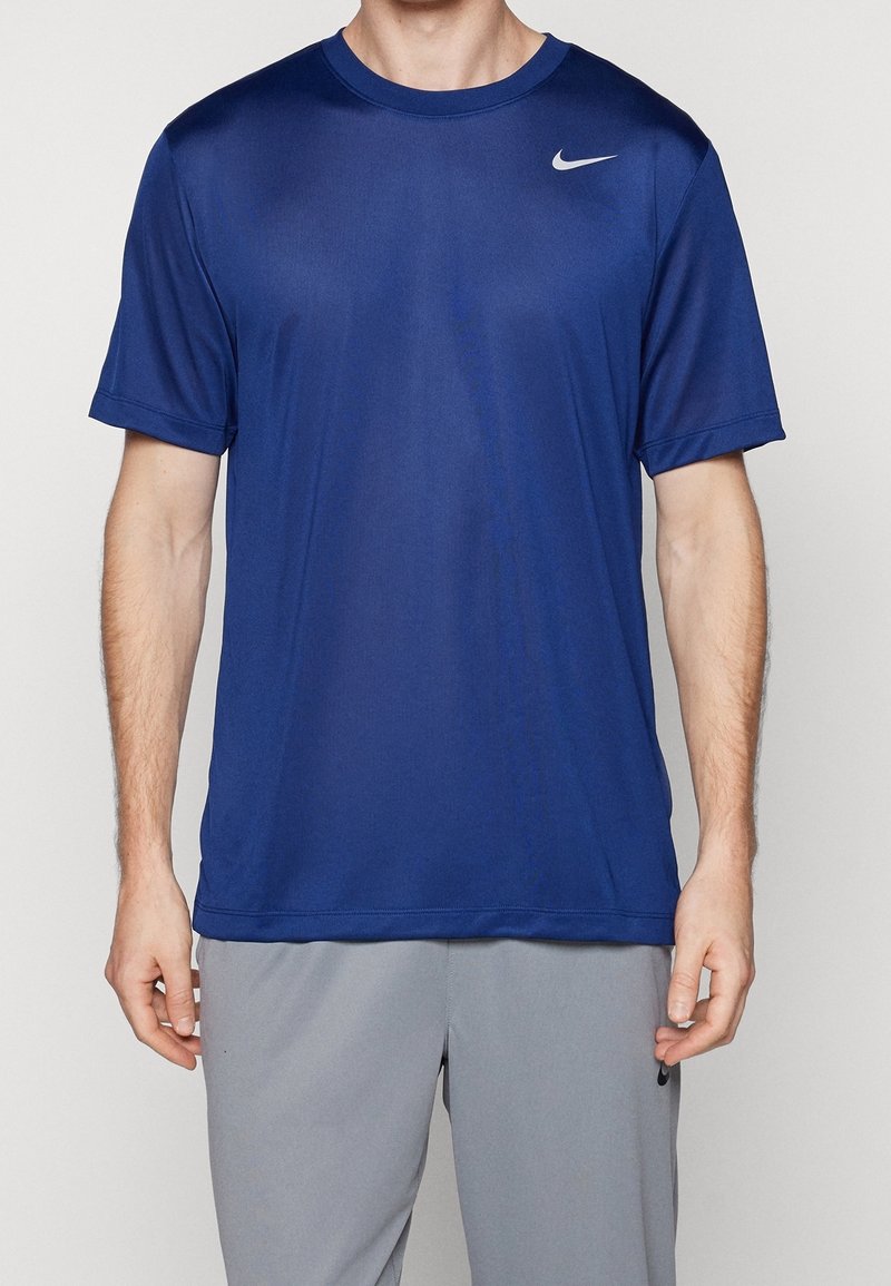 Camiseta deportiva azul hecha de tejido ligero, de manga corta, con cuello redondo, que presenta un pequeño logotipo blanco de Nike en el lado izquierdo del pecho.