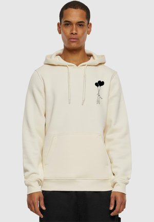 Cream hoodie made of cotton blend, featuring a front pocket and black graphic of a figure holding three balloons on the left chest area.