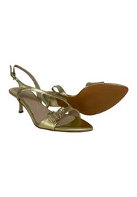 Scarpe slingback metallizzate dorate con tacco medio, punta aperta, due accenti di cristallo sulla cinghia e suola marrone texturizzata.