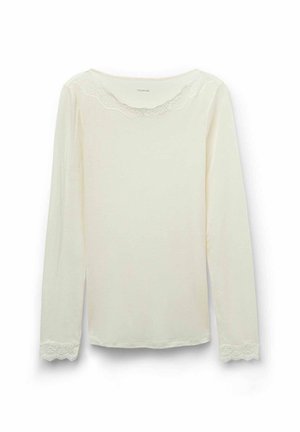 Blouse crème à manches longues avec des dentelles au niveau de l'encolure et des manchettes, fabriquée à partir d'un tissu doux, présentant une coupe décontractée et une encolure ronde.