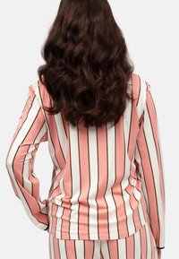 Długi rękaw w kolorze różowym z białymi pionowymi paskami i czarnymi akcentami. Miękka tkanina o dopasowanym kroju, z okrągłym dekoltem i subtelnymi detalami szwów.