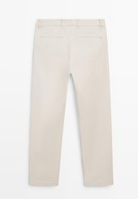 Pantalon beige coupe slim avec passants pour ceinture et deux poches arrière passepoilées, présenté à plat montrant le côté dos.