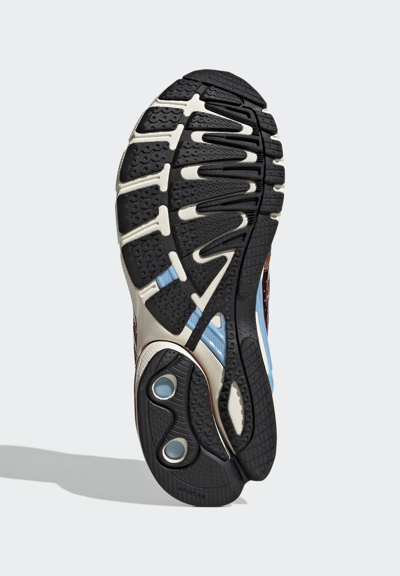 Semelle en caoutchouc noir avec motifs texturés; accents bleus et crème remarquables; forme incurvée avec des crêtes proéminentes pour la traction.